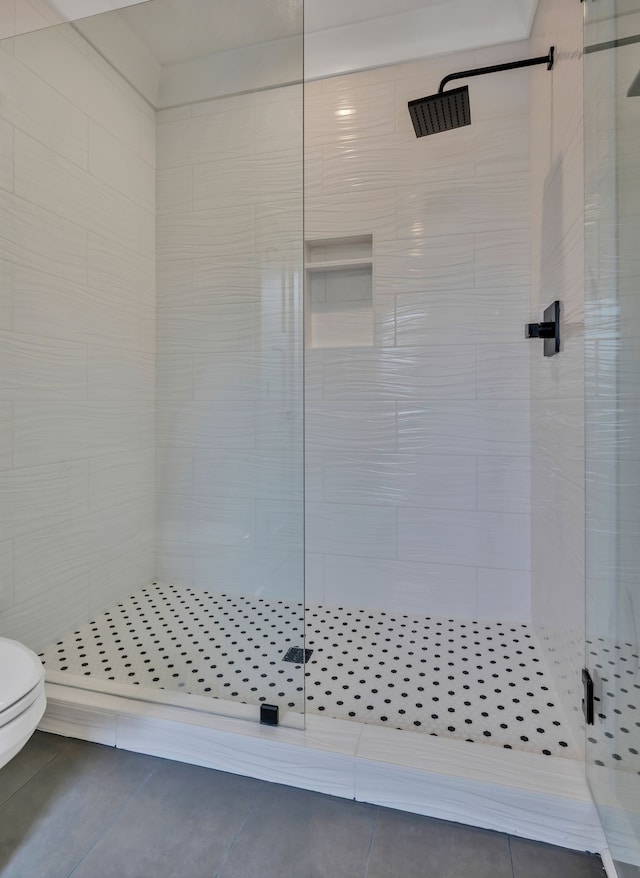 bathroom with tile patterned floors, toilet, and a shower with shower door