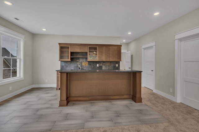 kitchen with a kitchen breakfast bar, light carpet, backsplash, and sink