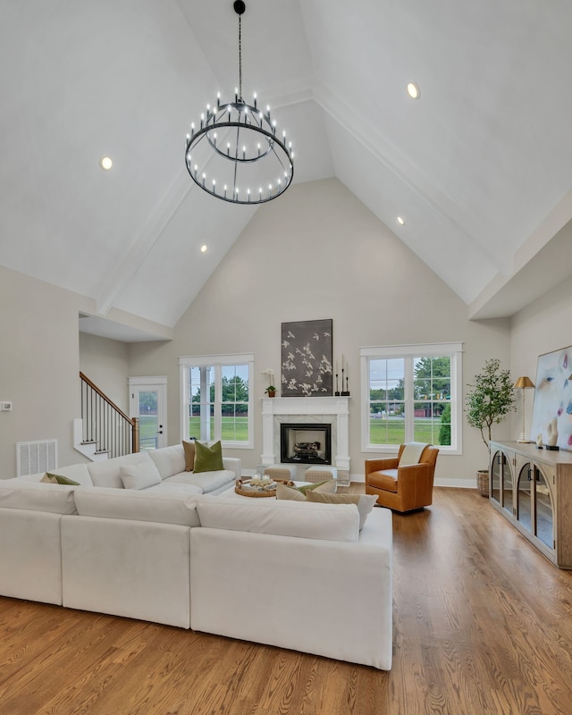 living room featuring a premium fireplace, a healthy amount of sunlight, hardwood / wood-style floors, and a chandelier