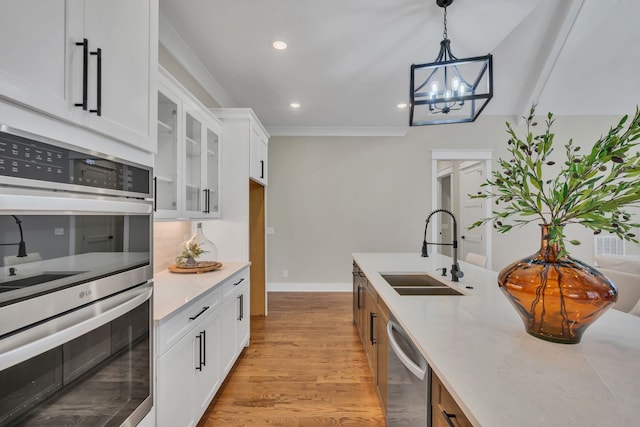 kitchen featuring decorative light fixtures, a notable chandelier, stainless steel appliances, sink, and white cabinetry