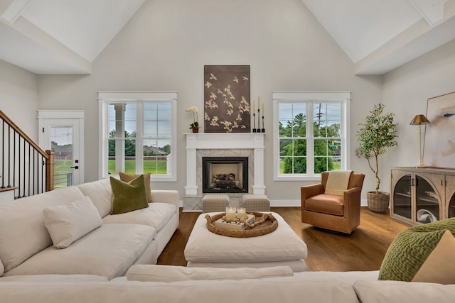 living room featuring plenty of natural light, high vaulted ceiling, wood-type flooring, and a tile fireplace