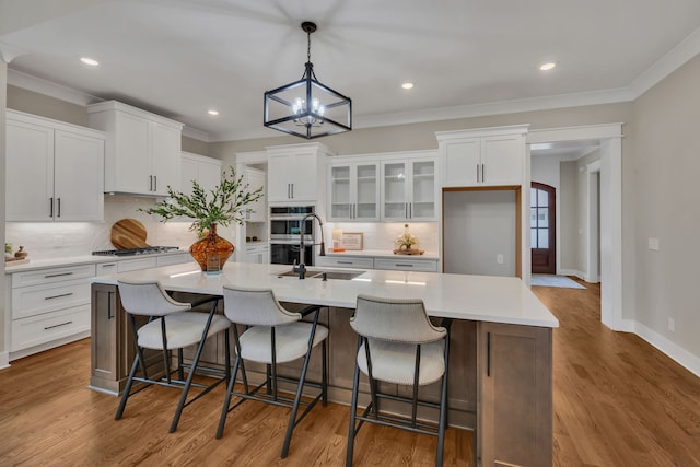 kitchen with a notable chandelier, sink, a center island with sink, and white cabinets