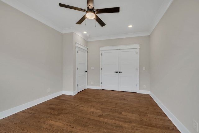 unfurnished bedroom featuring crown molding, dark wood-type flooring, ceiling fan, and a closet