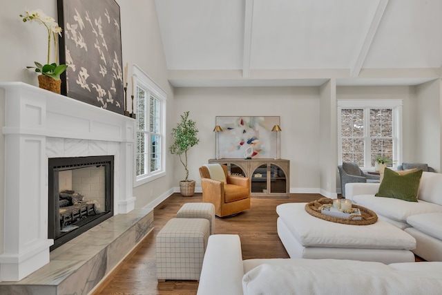 living room featuring hardwood / wood-style floors, vaulted ceiling with beams, and a premium fireplace