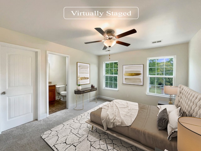 bedroom with ceiling fan, light colored carpet, and connected bathroom