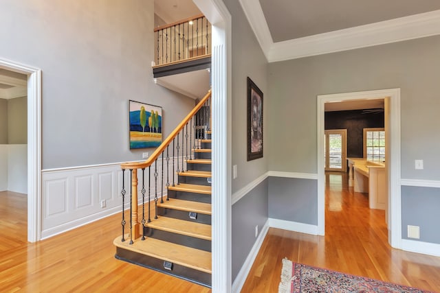 stairway with wood-type flooring and crown molding