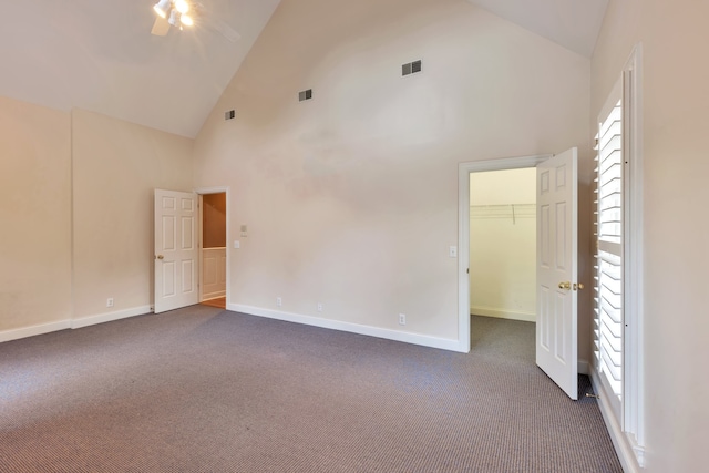 unfurnished room with dark colored carpet and high vaulted ceiling