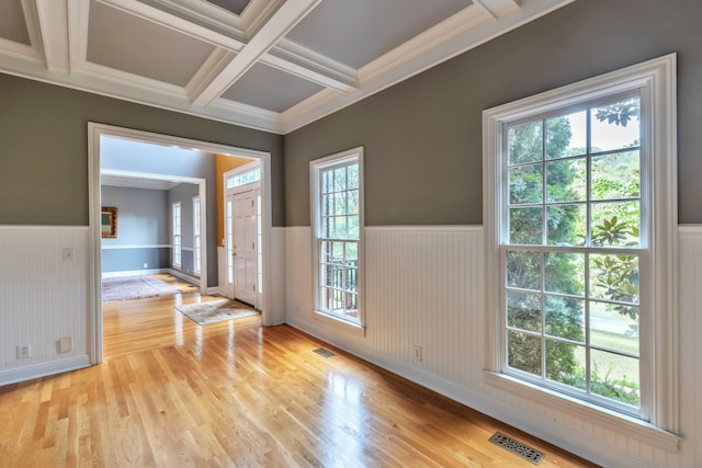 empty room featuring beam ceiling, plenty of natural light, coffered ceiling, and light hardwood / wood-style flooring