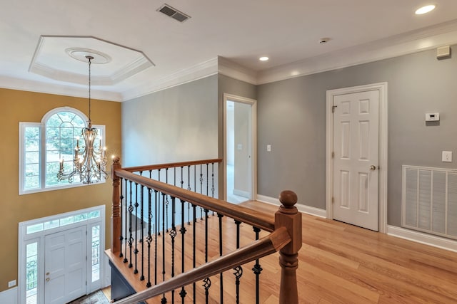 hall featuring a notable chandelier, light wood-type flooring, and ornamental molding