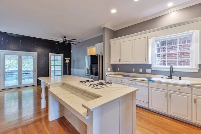 kitchen with white appliances, white cabinets, a kitchen island, and a wealth of natural light