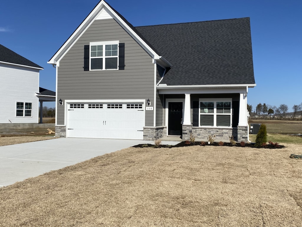 view of front of house with covered porch, a front yard, and a garage