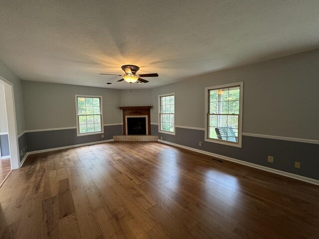 unfurnished living room featuring dark wood-type flooring, ceiling fan, and a textured ceiling