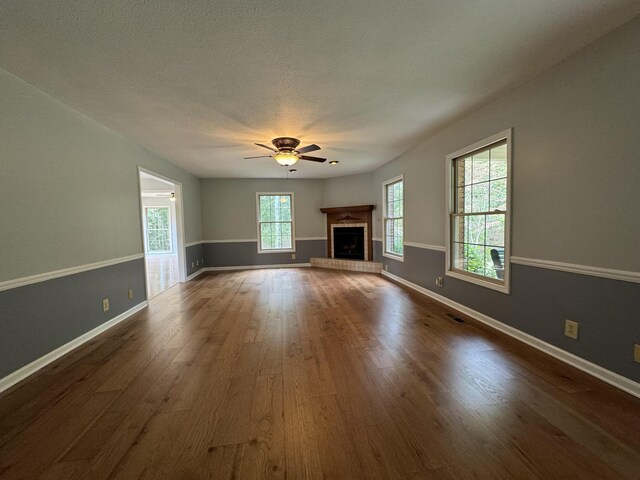 unfurnished living room with wood-type flooring, a textured ceiling, and ceiling fan