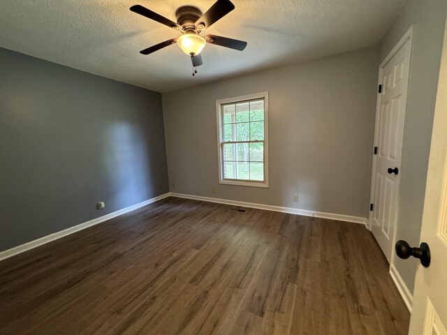 empty room featuring dark wood-type flooring, a textured ceiling, and ceiling fan