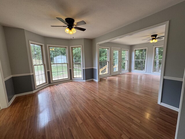 unfurnished living room with ceiling fan, hardwood / wood-style flooring, and a healthy amount of sunlight