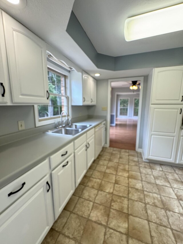 kitchen with ceiling fan, white dishwasher, white cabinetry, and sink