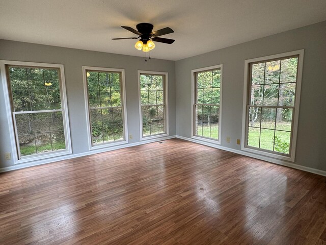 spare room with hardwood / wood-style floors, ceiling fan, and a healthy amount of sunlight