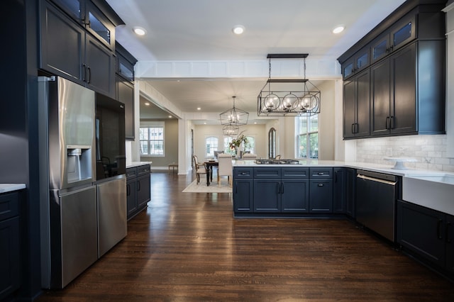 kitchen with dark hardwood / wood-style flooring, a notable chandelier, hanging light fixtures, stainless steel appliances, and kitchen peninsula