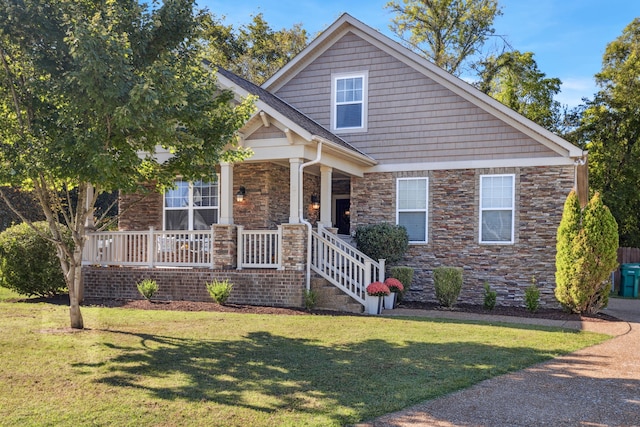 craftsman-style home featuring covered porch and a front yard