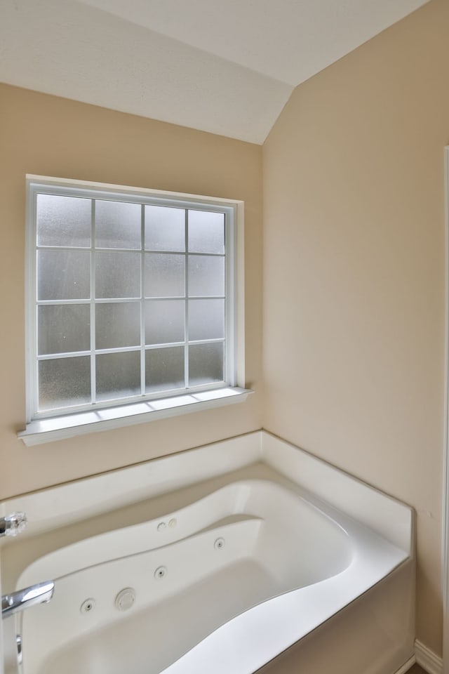 bathroom with lofted ceiling and a bathtub