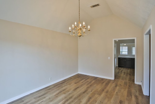 empty room featuring lofted ceiling, a chandelier, and hardwood / wood-style floors