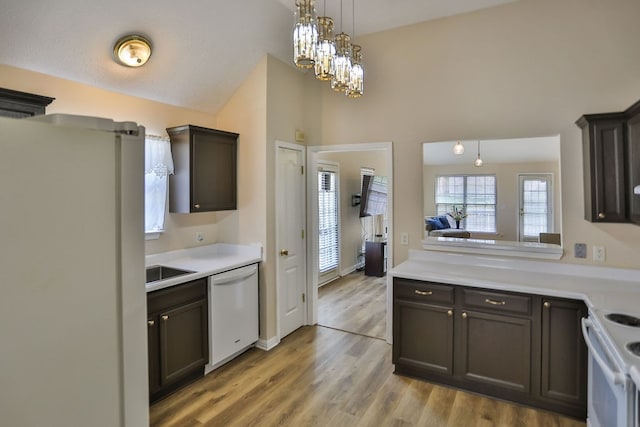 kitchen featuring light wood-type flooring, white appliances, lofted ceiling, and dark brown cabinets