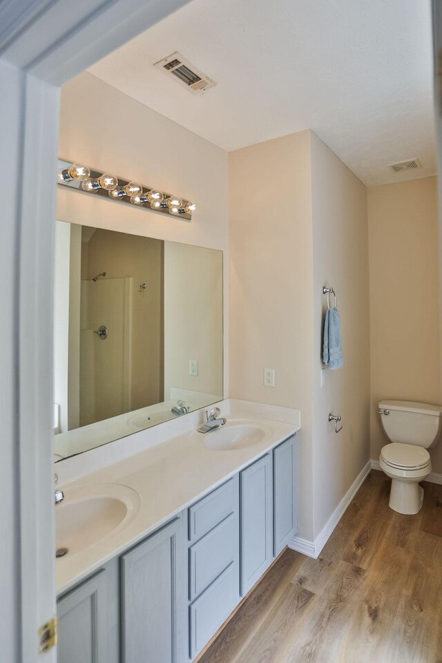 bathroom with walk in shower, vanity, toilet, and hardwood / wood-style flooring