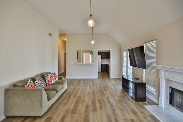 living room featuring a high end fireplace, vaulted ceiling, and hardwood / wood-style flooring