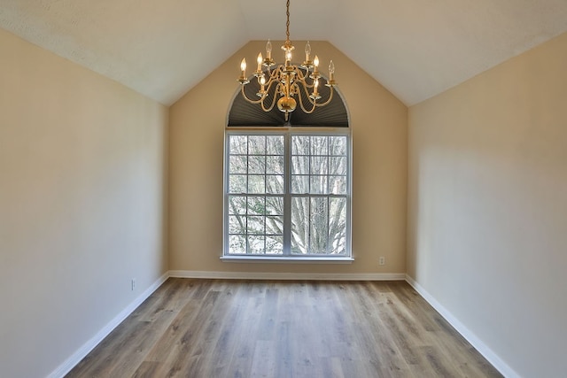 spare room with lofted ceiling, a wealth of natural light, and hardwood / wood-style floors