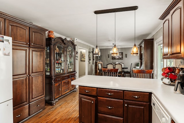 kitchen featuring light wood-type flooring, crown molding, decorative light fixtures, dishwashing machine, and white refrigerator