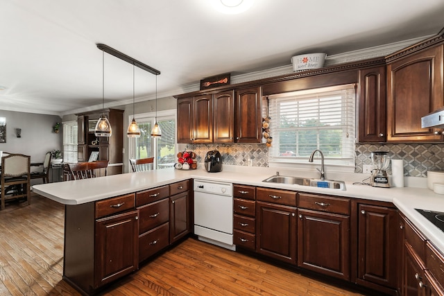 kitchen featuring hanging light fixtures, dishwasher, backsplash, sink, and kitchen peninsula