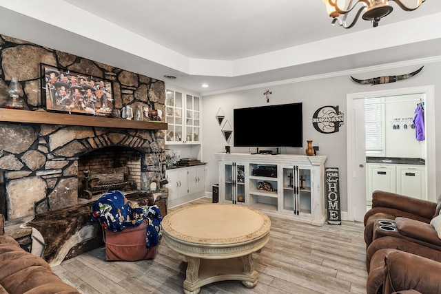 living room featuring crown molding, light hardwood / wood-style floors, a chandelier, and a fireplace