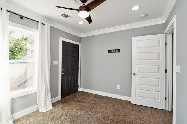 foyer entrance featuring ceiling fan, dark carpet, and crown molding