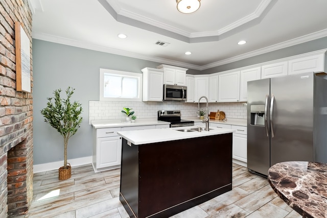 kitchen featuring appliances with stainless steel finishes, white cabinetry, a kitchen island with sink, and ornamental molding