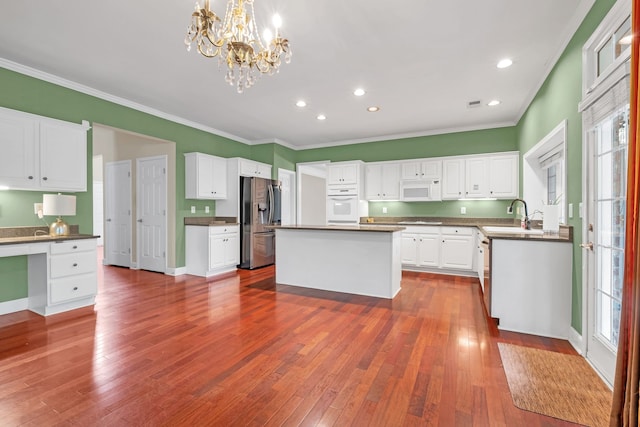 kitchen featuring white appliances, a healthy amount of sunlight, wood-type flooring, and white cabinets