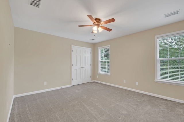 carpeted spare room featuring a healthy amount of sunlight and ceiling fan