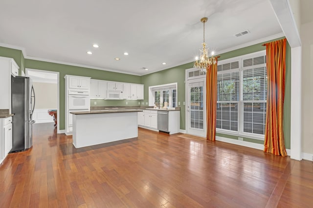 kitchen with appliances with stainless steel finishes, wood-type flooring, a center island, and white cabinets