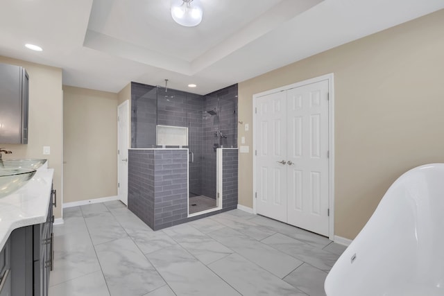 bathroom featuring independent shower and bath, a raised ceiling, and vanity