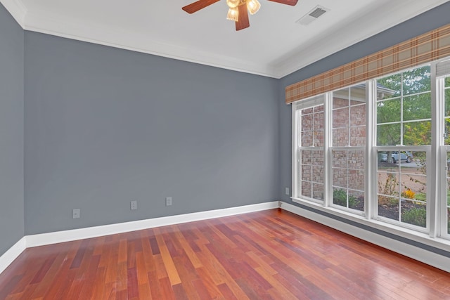 empty room featuring a healthy amount of sunlight, ceiling fan, ornamental molding, and hardwood / wood-style flooring