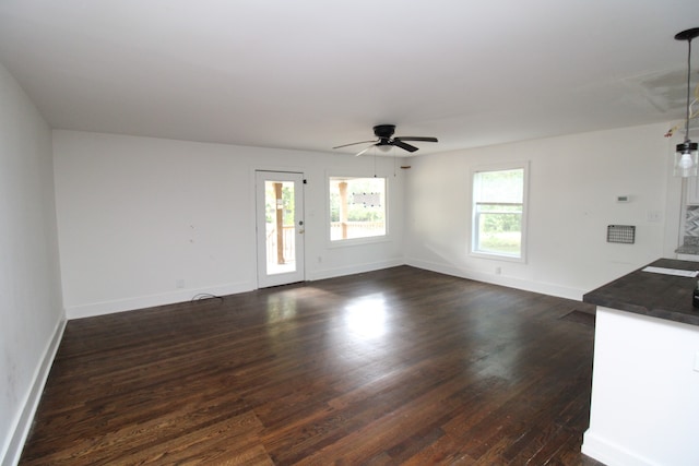 unfurnished living room featuring dark wood-type flooring and ceiling fan