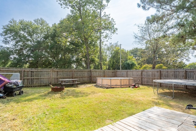 view of yard with a pool side deck and a trampoline