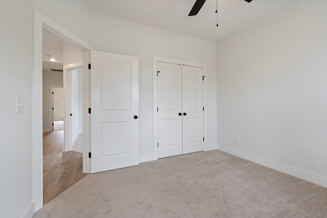 unfurnished bedroom featuring light carpet, a closet, and ceiling fan