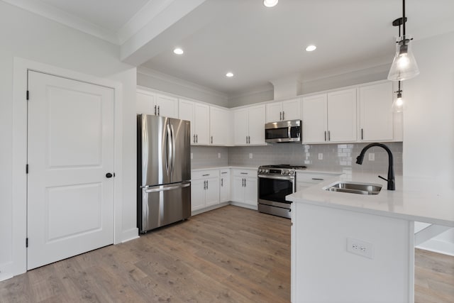 kitchen featuring white cabinets, pendant lighting, sink, appliances with stainless steel finishes, and light wood-type flooring