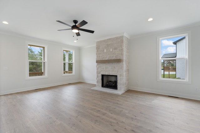 unfurnished living room featuring ceiling fan, ornamental molding, a fireplace, and light hardwood / wood-style floors