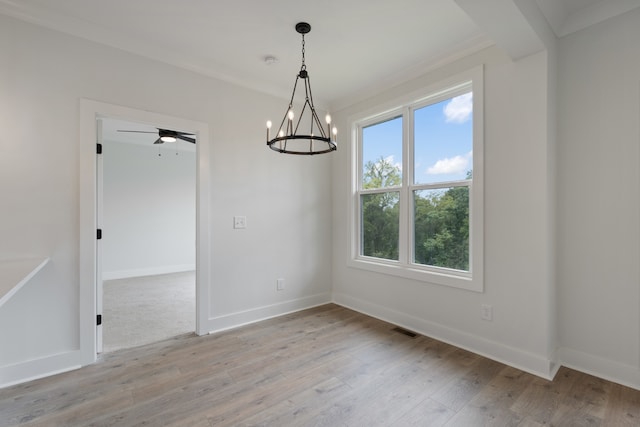 unfurnished dining area with ceiling fan with notable chandelier, ornamental molding, and light hardwood / wood-style flooring