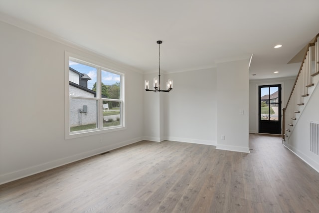 unfurnished dining area with crown molding, an inviting chandelier, and light hardwood / wood-style flooring