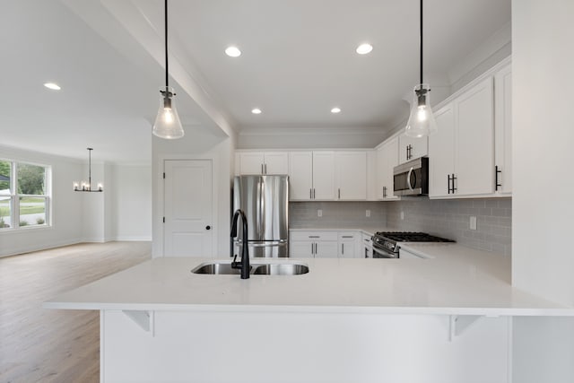 kitchen featuring stainless steel appliances, white cabinetry, kitchen peninsula, and sink