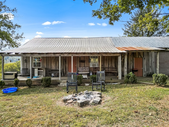 back of house featuring a lawn and a fire pit