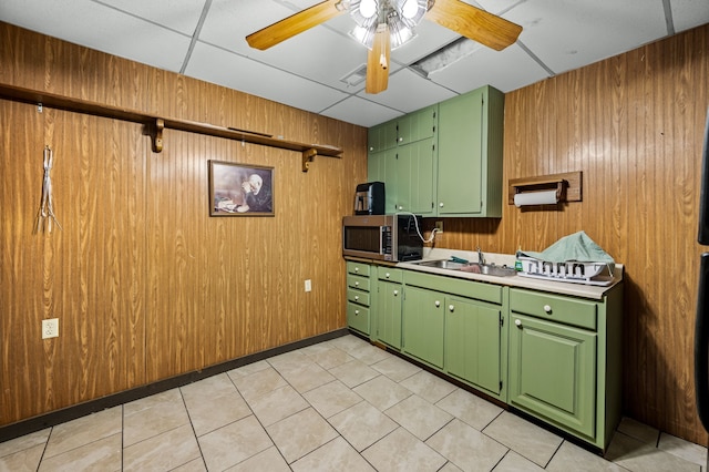 kitchen with ceiling fan, green cabinets, wood walls, and sink