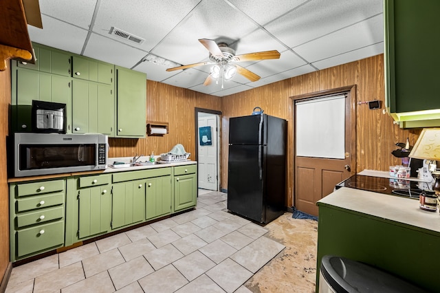 kitchen with a drop ceiling, green cabinetry, ceiling fan, and black fridge